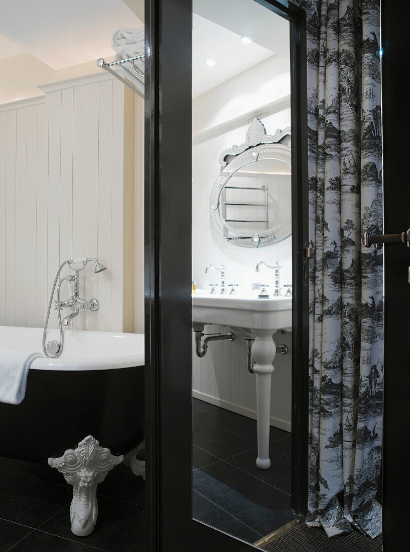 Black and white, retro bathroom with pedestal washstand, claw-footed bathtub and wood-panelled walls