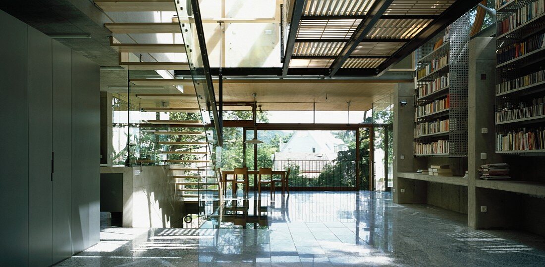 Contemporary solar house building - airy staircase to gallery with sun from above and dining area in front of wide glass wall