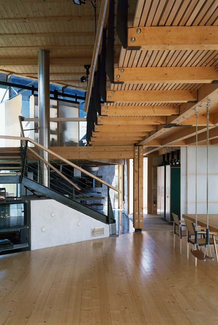 Schaukel im offenen Wohnraum unter Galerie, Edelstahl-Kaminrohr und Stahlkonstruktionen im modernen Holzhaus
