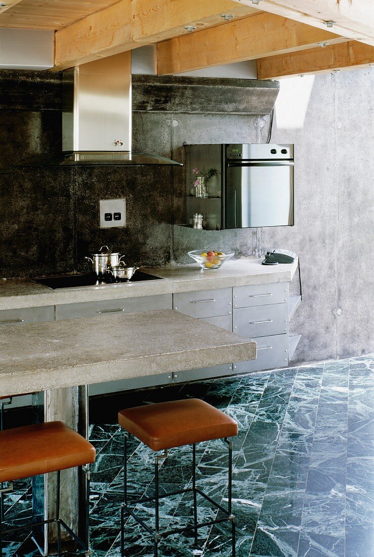 Betonplatten auf Küchenzeile und Esstisch, schwarzweisse Steinplatten und schwarz marmorierte Rückwand in modernem Holzhaus