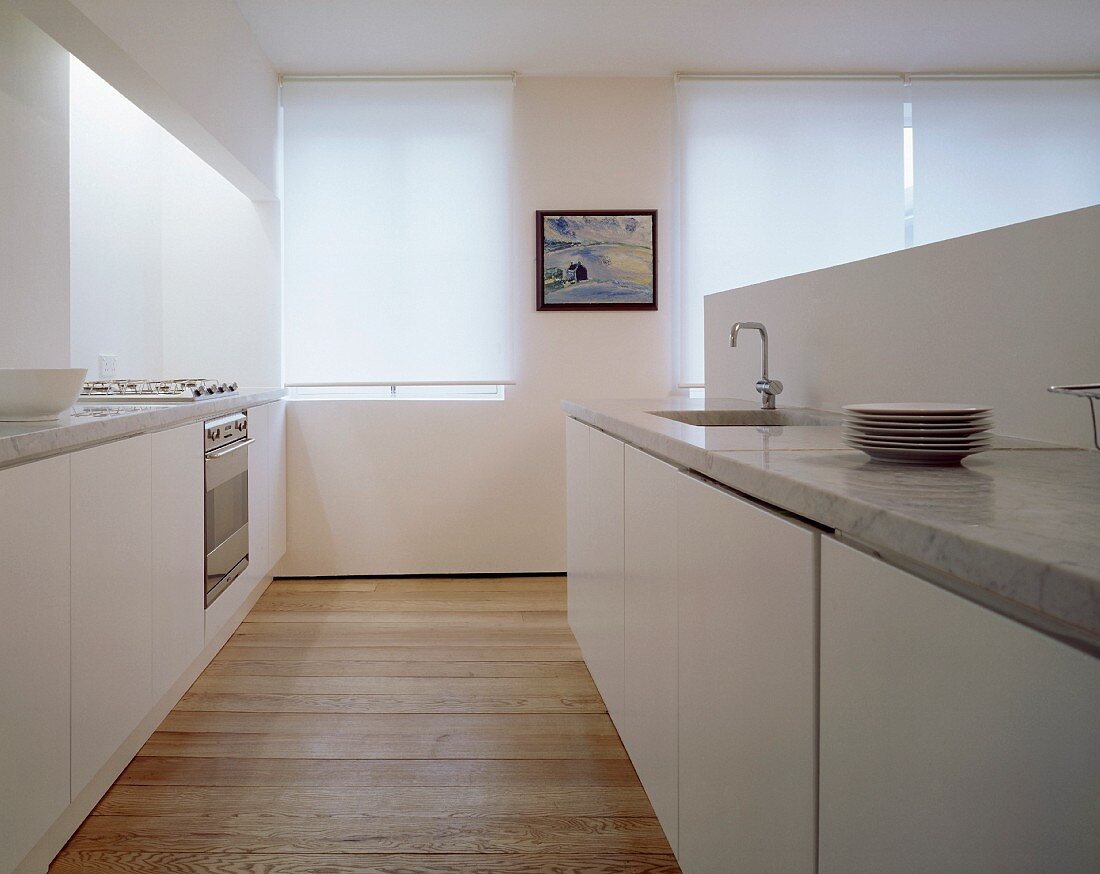 Moderne, weiße Küche mit glatten Fronten und Steinarbeitsplatten