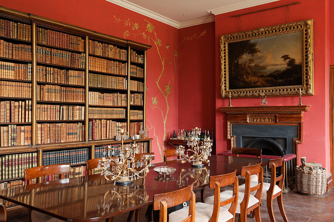 Library room with red walls and golden ornaments, antique books and paintings