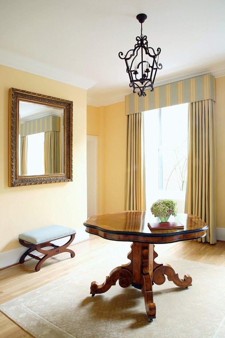 Antike Einzelstücke und gestreifter Vorhang mit passender Schabracke in traditionellem Wohnzimmer