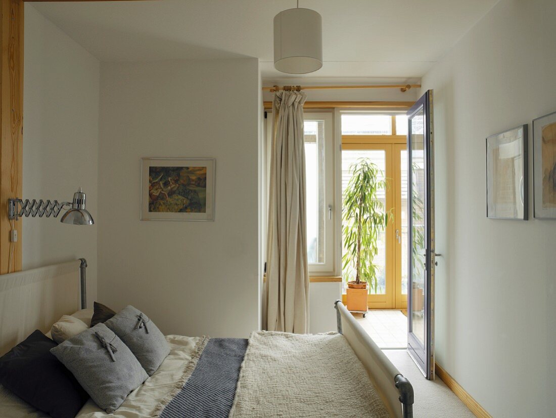 Kleines, einfaches Schlafzimmer - Doppelbett mit Stoffen im Landhausstil unter Retro-Lampe mit Scherenarm