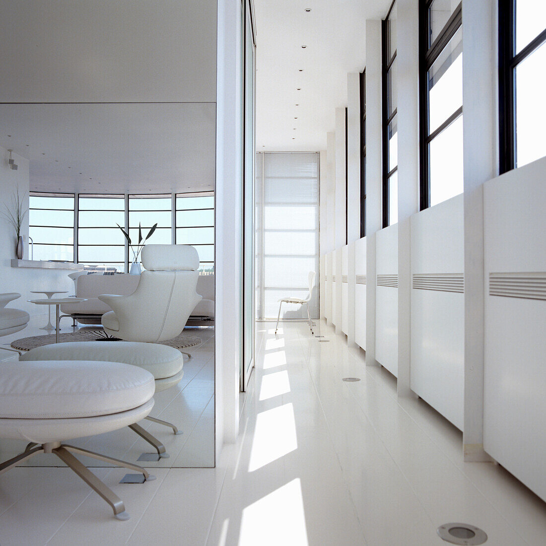 Modern living room in white with windows and leather armchairs