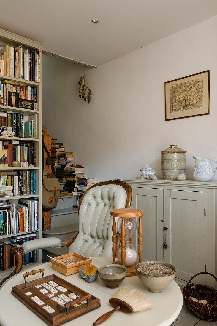 Reading corner with antique armchair, hourglass and wall shelf full of books