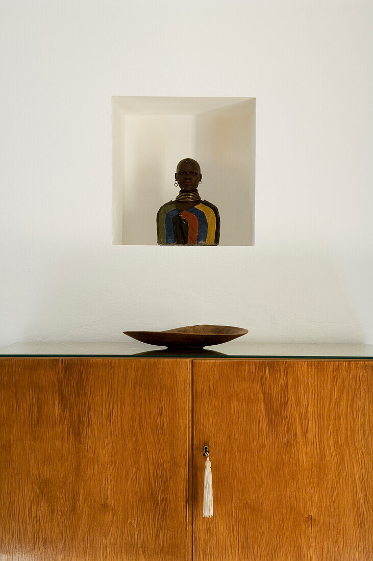 Wooden chest of drawers with bowl, figurine in wall niche