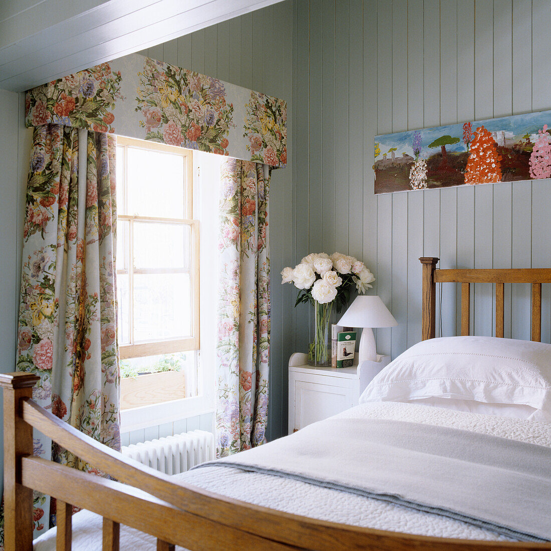 Schlafzimmer mit floral gemusterten Vorhängen und Holzbett