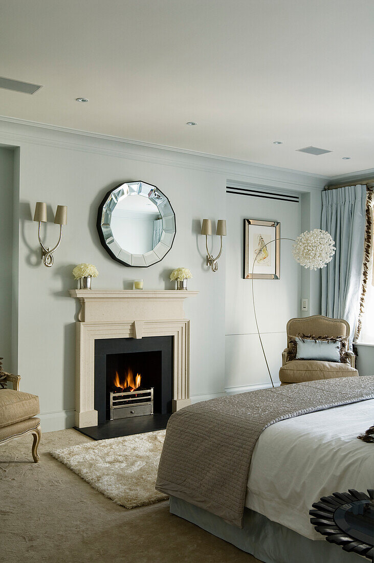 Bright bedroom with fireplace, wall mirror and walls in soft light blue