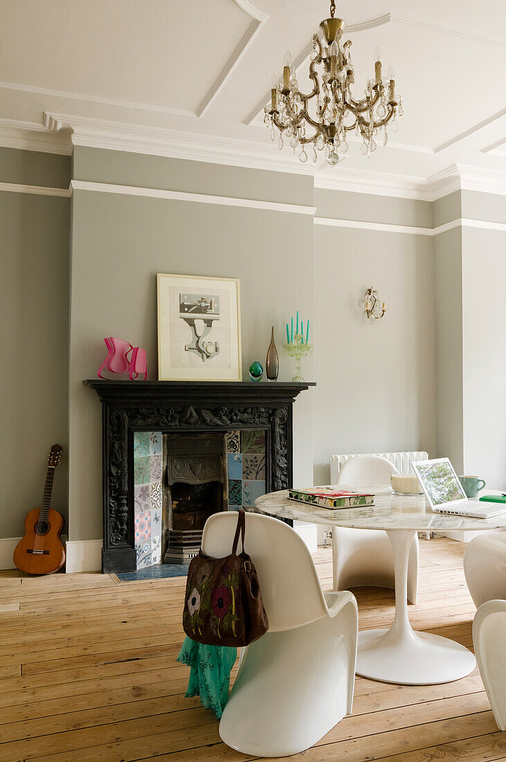 Living room with antique fireplace, white designer chairs and wooden flooring