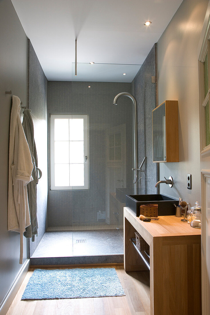 Modernes Bad mit Waschtisch aus Holz vor Duschbereich mit Glasabtrennung