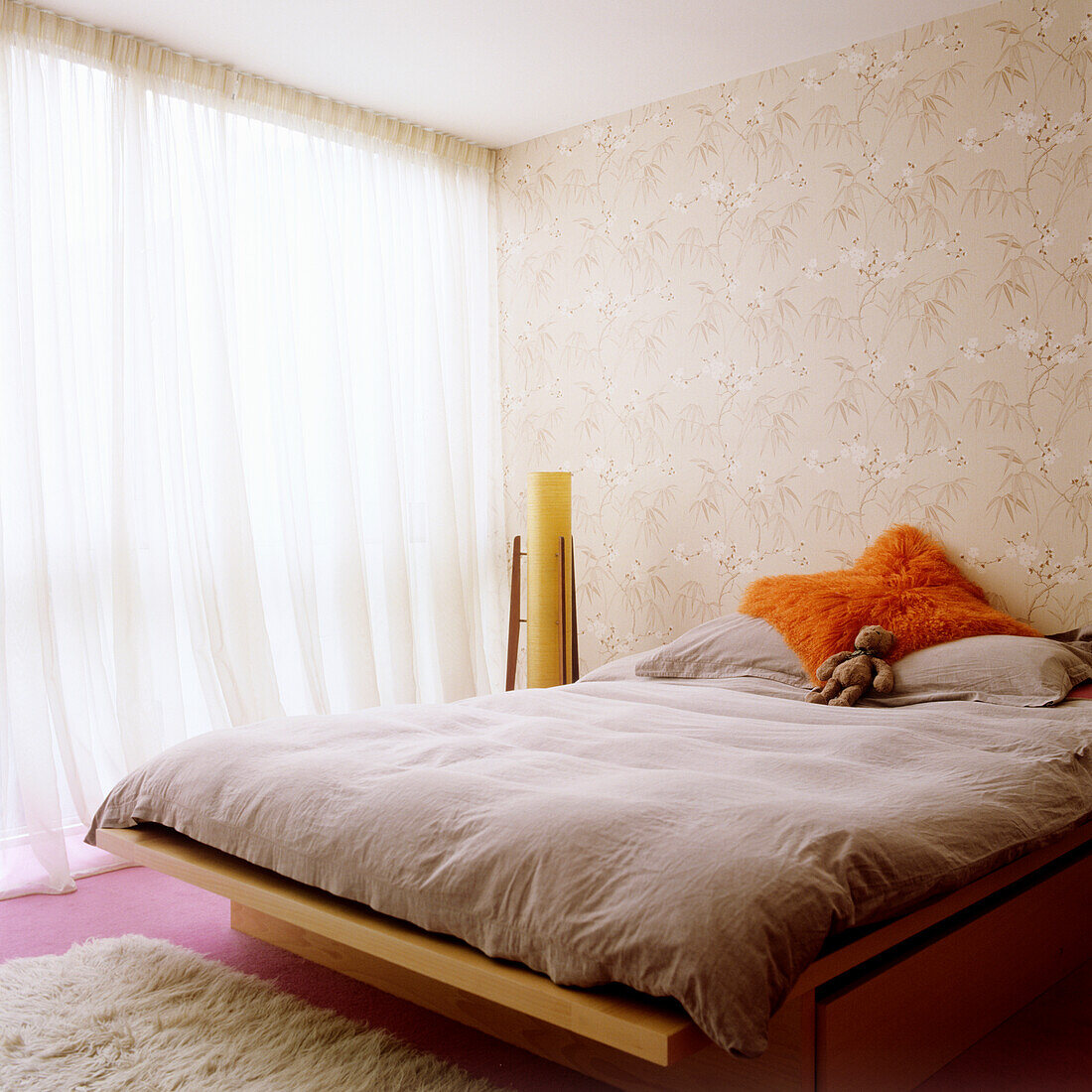 Bedroom with wooden bed, fluffy carpet and patterned wallpaper