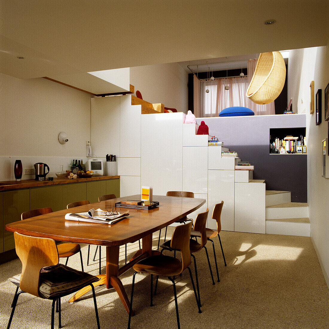 Kitchen in the basement with wooden table and chairs, staircase and view of hanging chairs