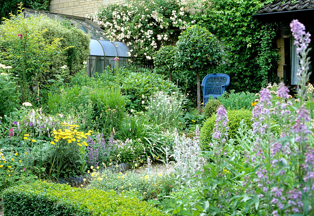 View of a diverse flower bed with garden chair in the background