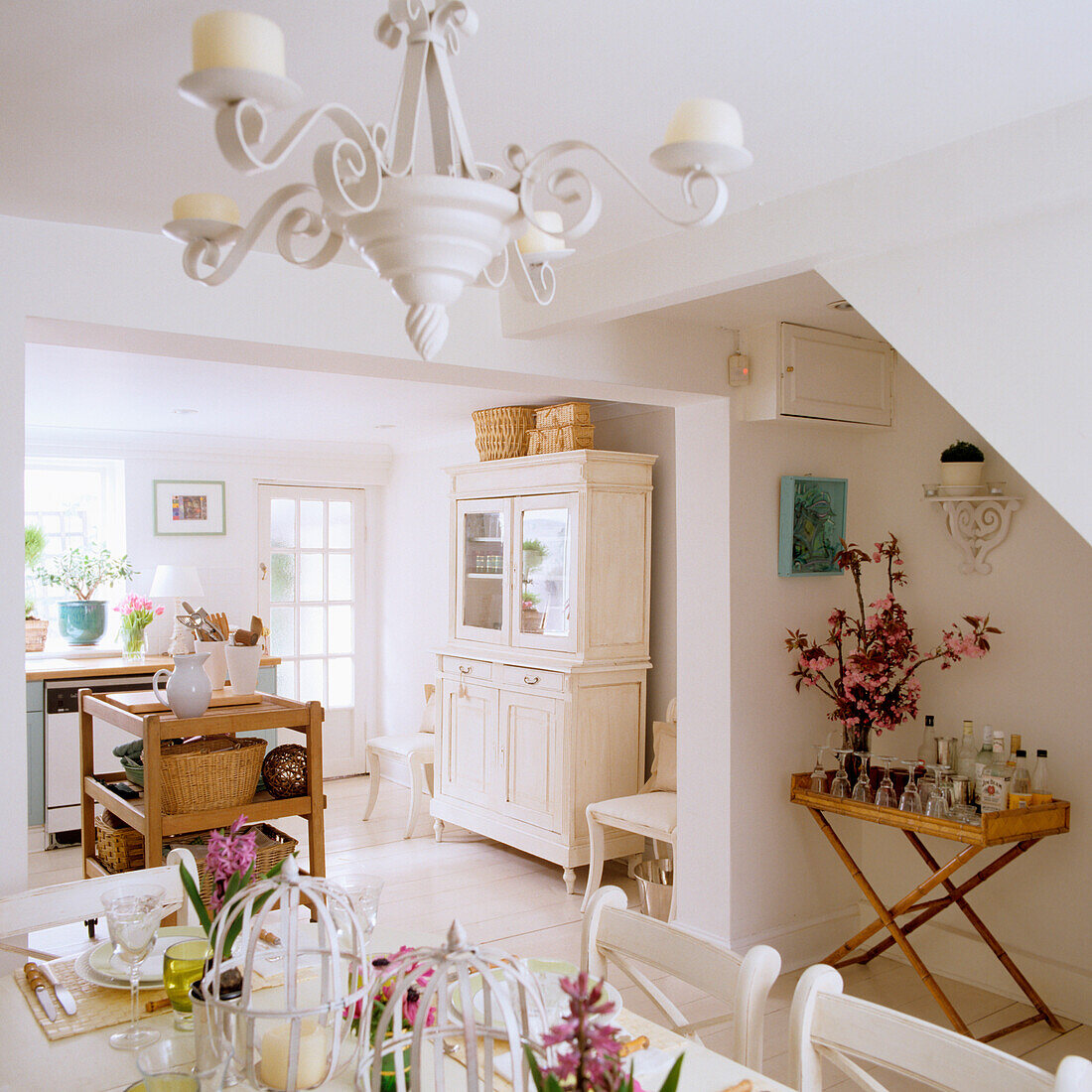 Open-plan kitchen with dining area, white furniture and chandelier