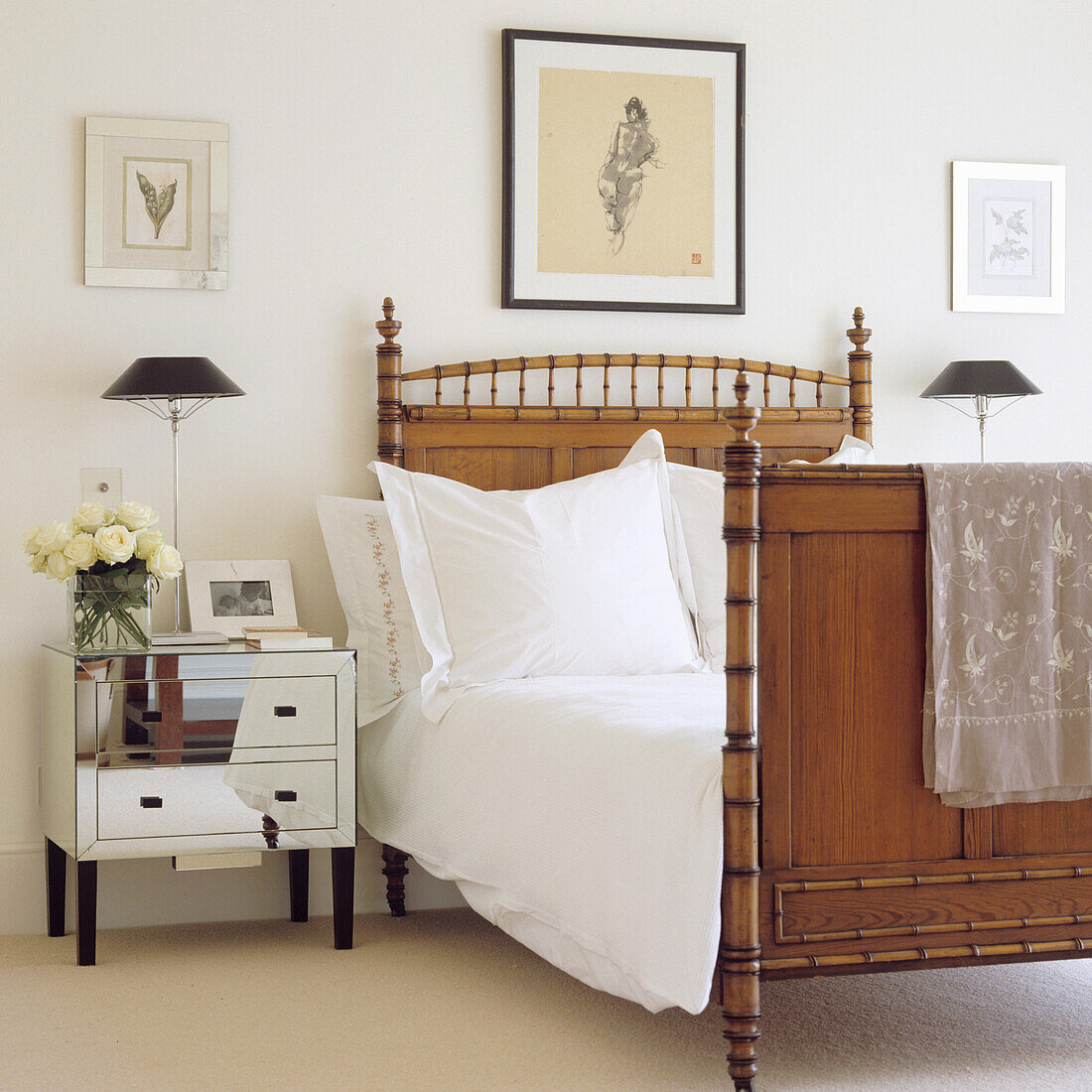 Wooden bed, bedside table with mirror element and pictures in bedroom