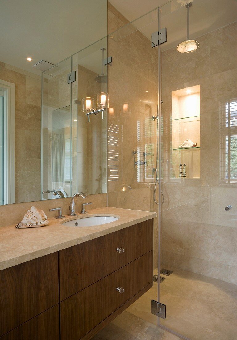 Badezimmer mit Marmorfliesen und mit Glastrennwand zum Duschbereich