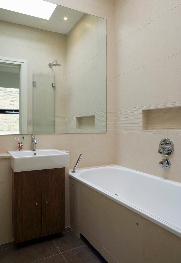 Badezimmer mit großem Spiegel, rechteckigem Waschbecken und Marmorfliesen
