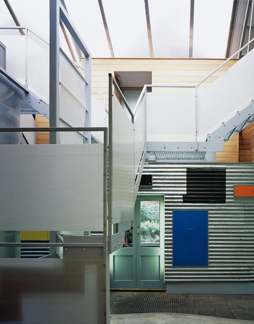 Staircase in open-plan living space with corrugated metal cladding on wall
