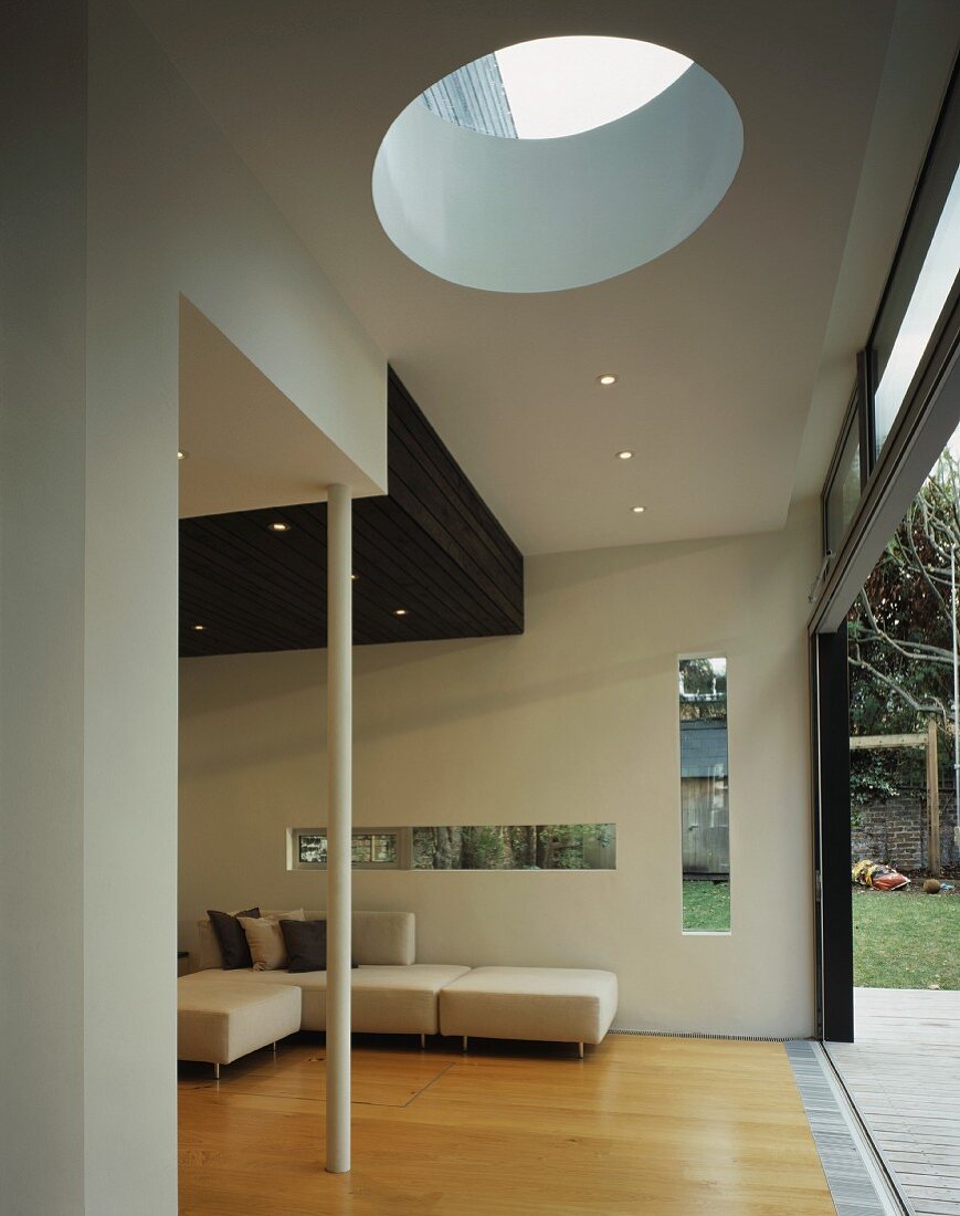 Stylish living space in house with window slits in wall and circular skylight in ceiling