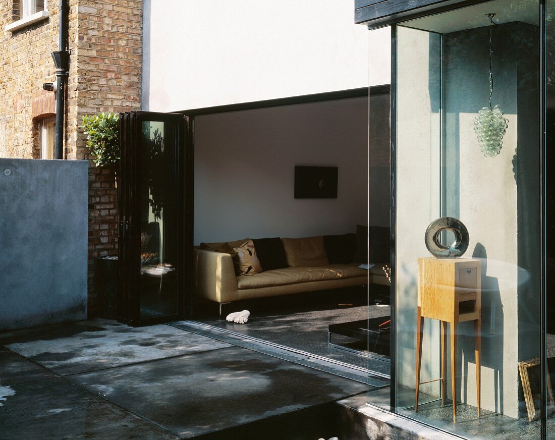 Terrasse vor dem Wohnraum mit geöffneter Falttür und Blick auf Sofa