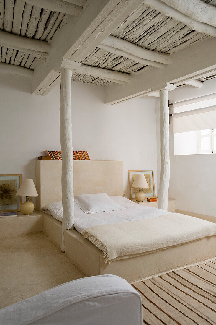 Bedroom with rustic wooden beamed ceiling in white and cream-coloured bed