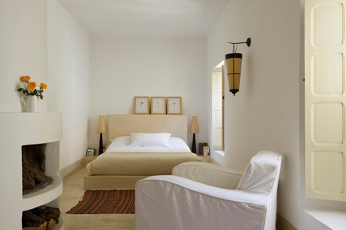 Bedroom with fireplace, bed and white armchair