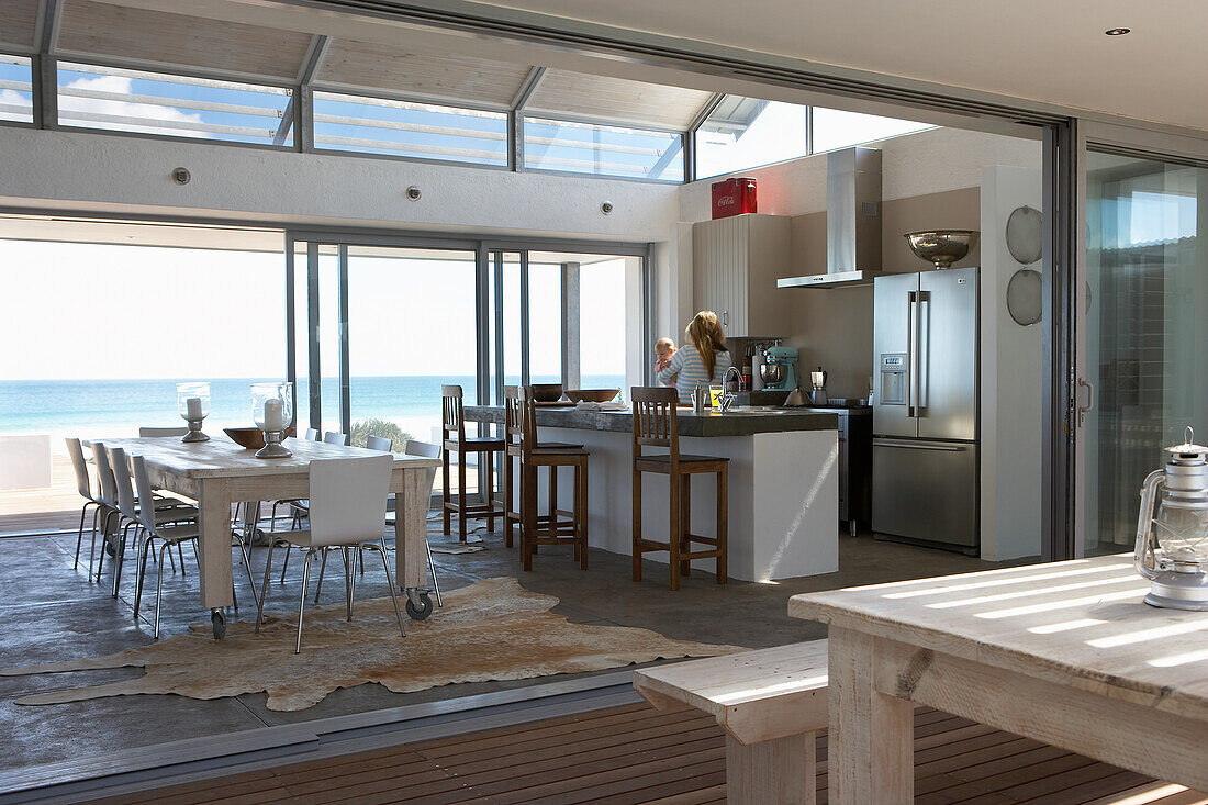 Modern kitchen with dining area and sea view through floor-to-ceiling windows