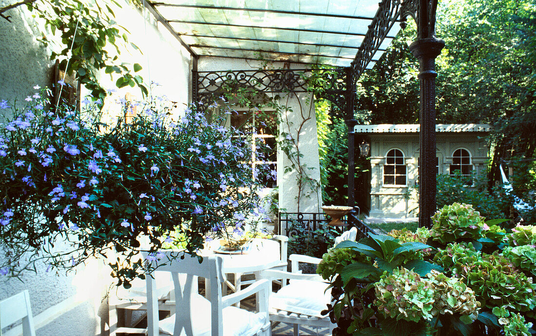 Verwunschener Garten und Gartenmöbel unter Pergola