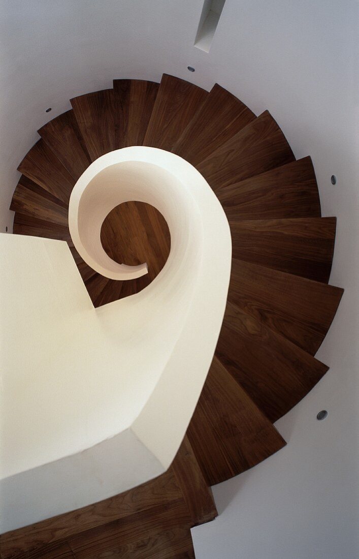 View of spiral stairwell with wooden treads and solid, white balustrade