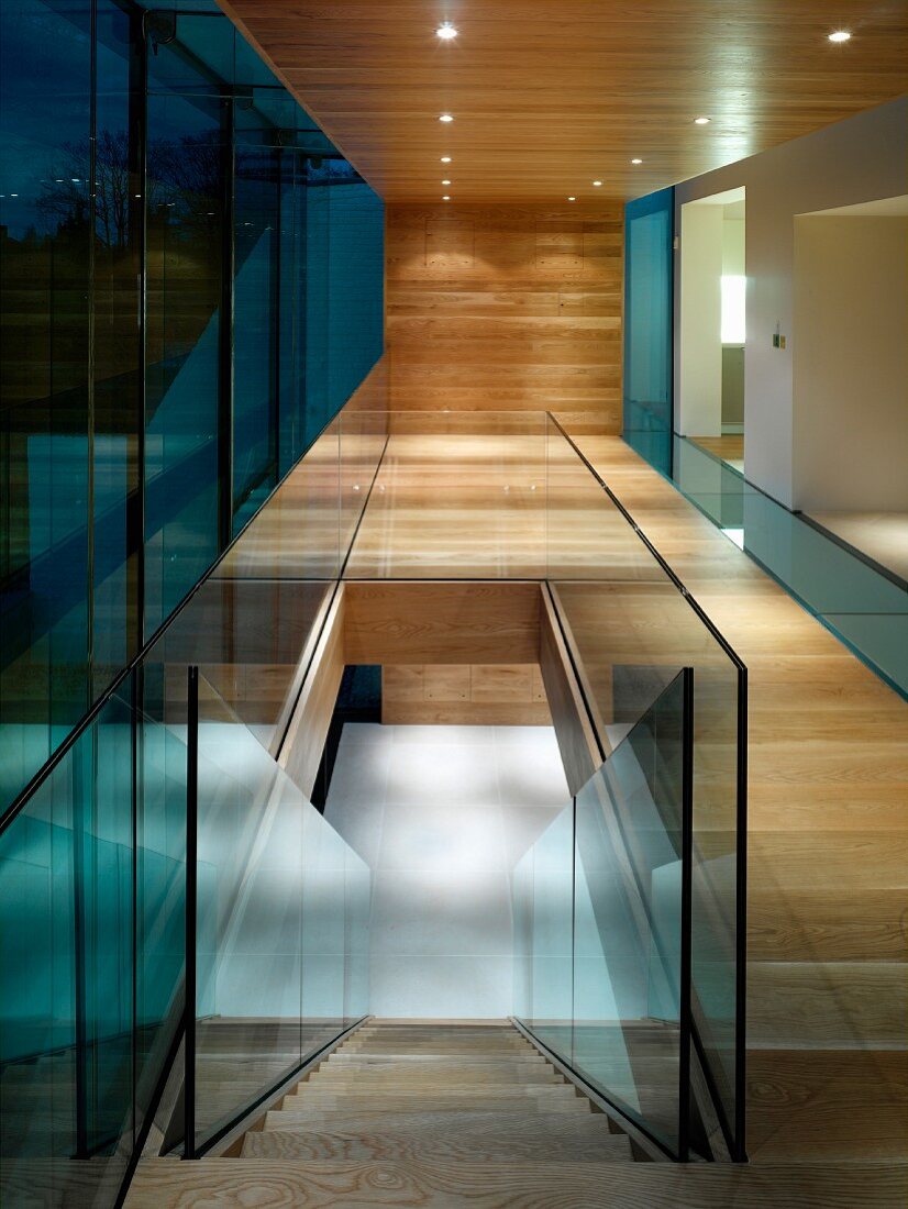 Contemporary building with glass wall in wood-clad hallway and view down staircase