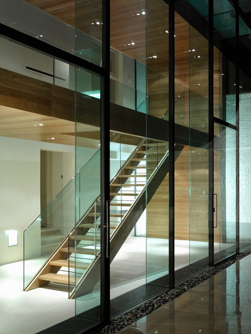 Glasfront eines zeitgenössischen Wohnhauses und Blick in beleuchteten Treppenraum