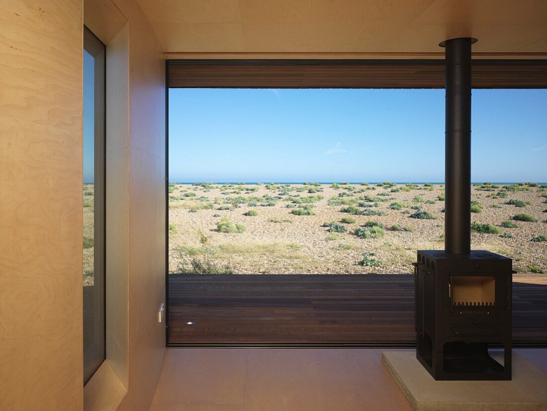 Free-standing, wood-burning stove in front of floor-to-ceiling windows with sea view