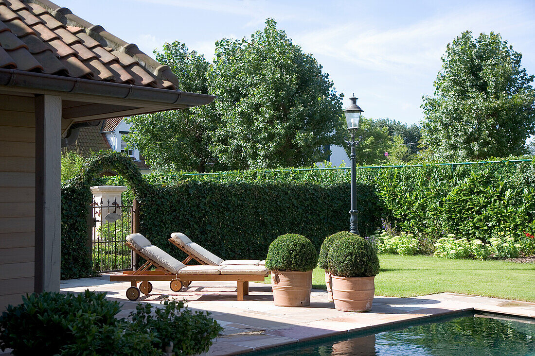 Well-kept pool area with sun loungers and topiary balls