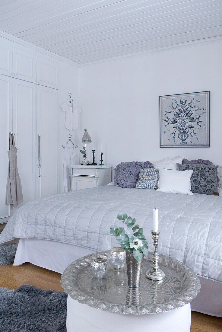 Schlafzimmer in Weiß mit gemusterten Kissen und silberfarbenen Dekoelementen