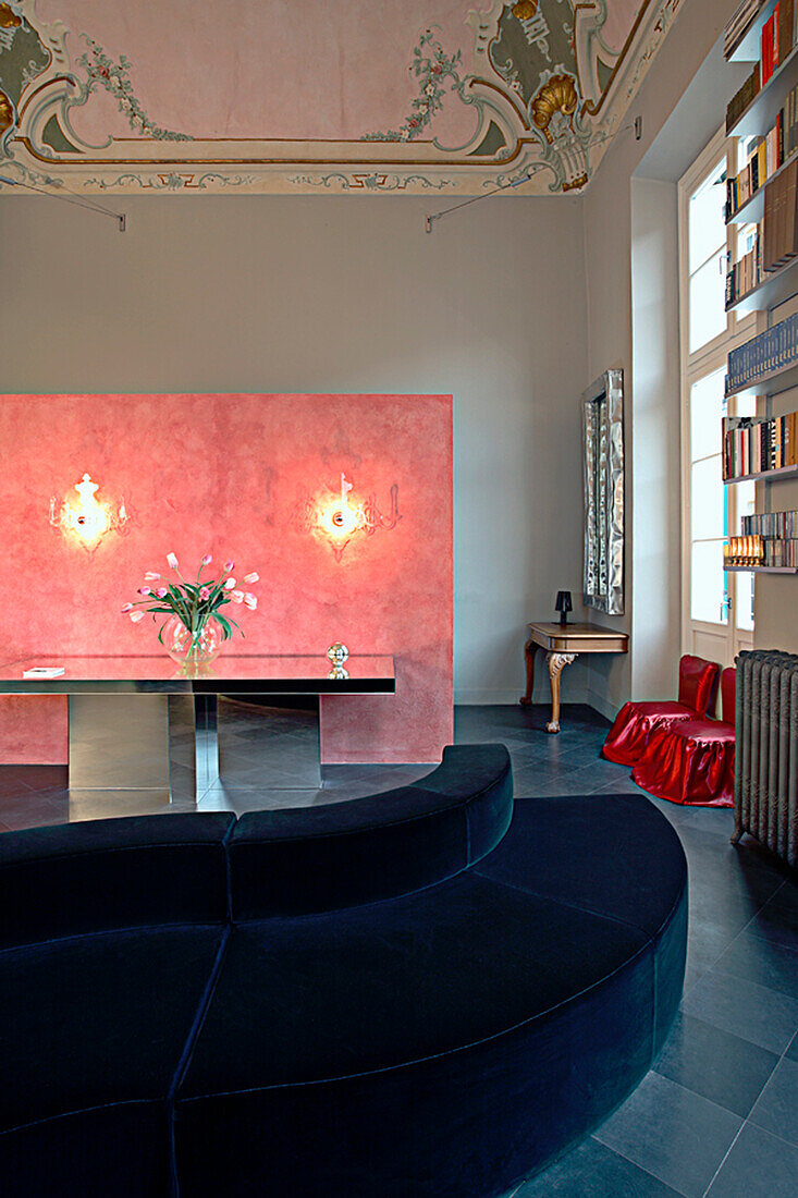 Velvet sofa and pink wall in historic living room with stucco ceiling