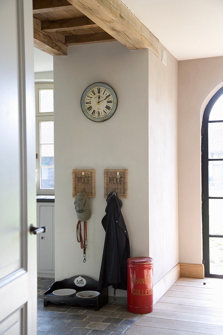 Cloakroom area with dog feeding bowls and antique wall clock below exposed ceiling beams
