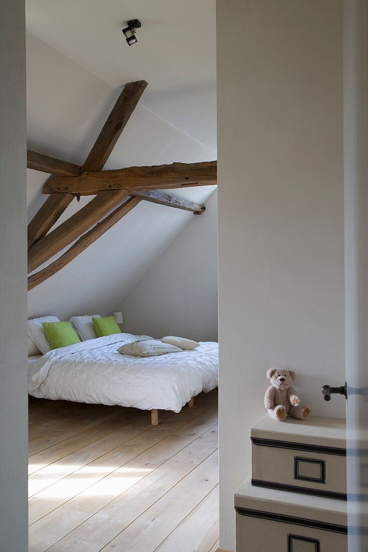 View into bedroom with double bed below exposed roof structure