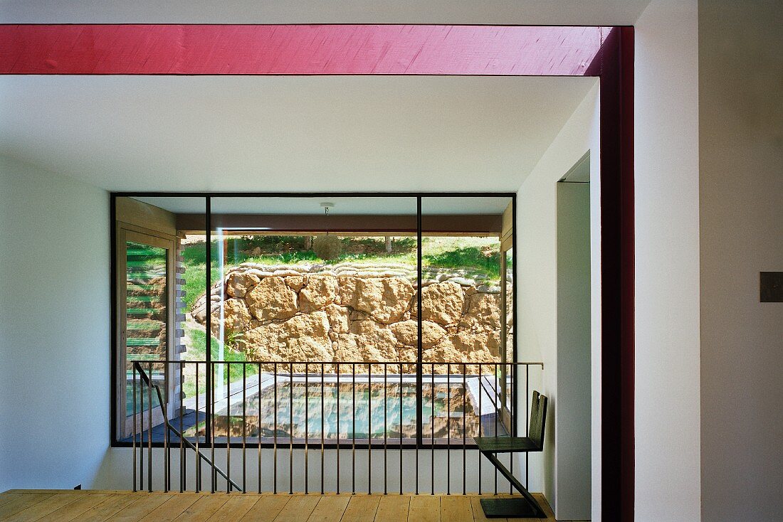 Blick vom Zwischengeschoss auf den Swimmingpool und die Natursteinwand