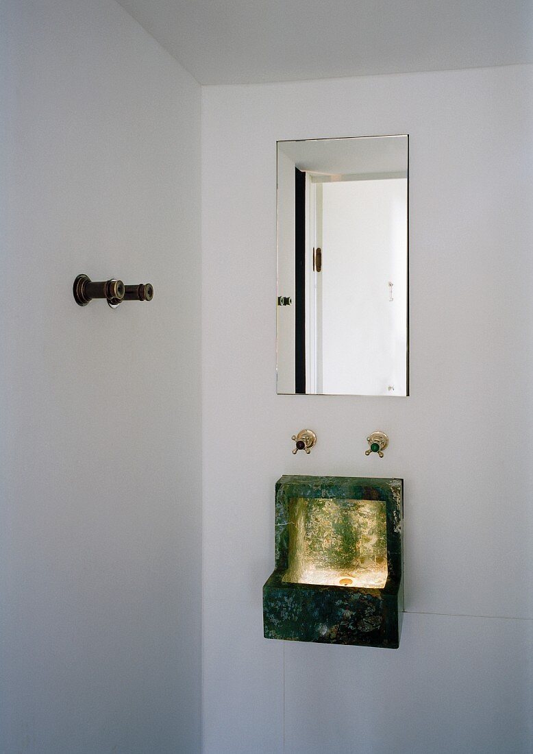 Kleines Waschbecken hängt an der Wand unter dem Spiegel