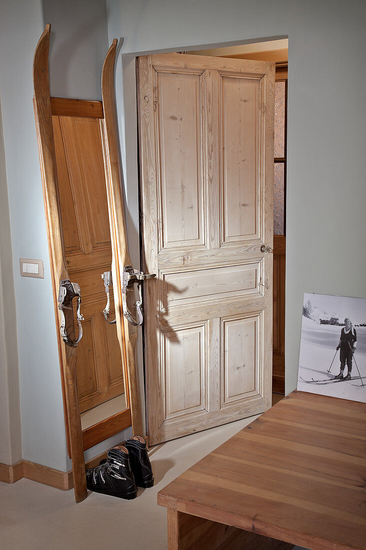 Selbstgebauter Standspiegel aus Vintage Skiern und Skischuhe neben offener Zimmertür