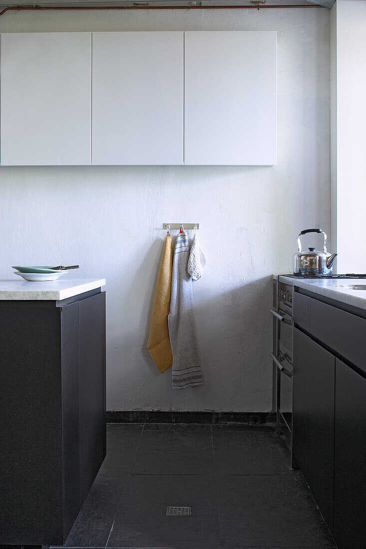 Kitchen with white wall and white wall units, black floor and black cupboards