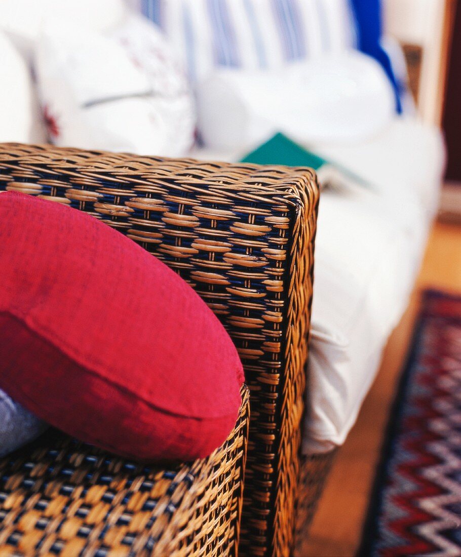Rattan armchair with red scatter cushion (detail)