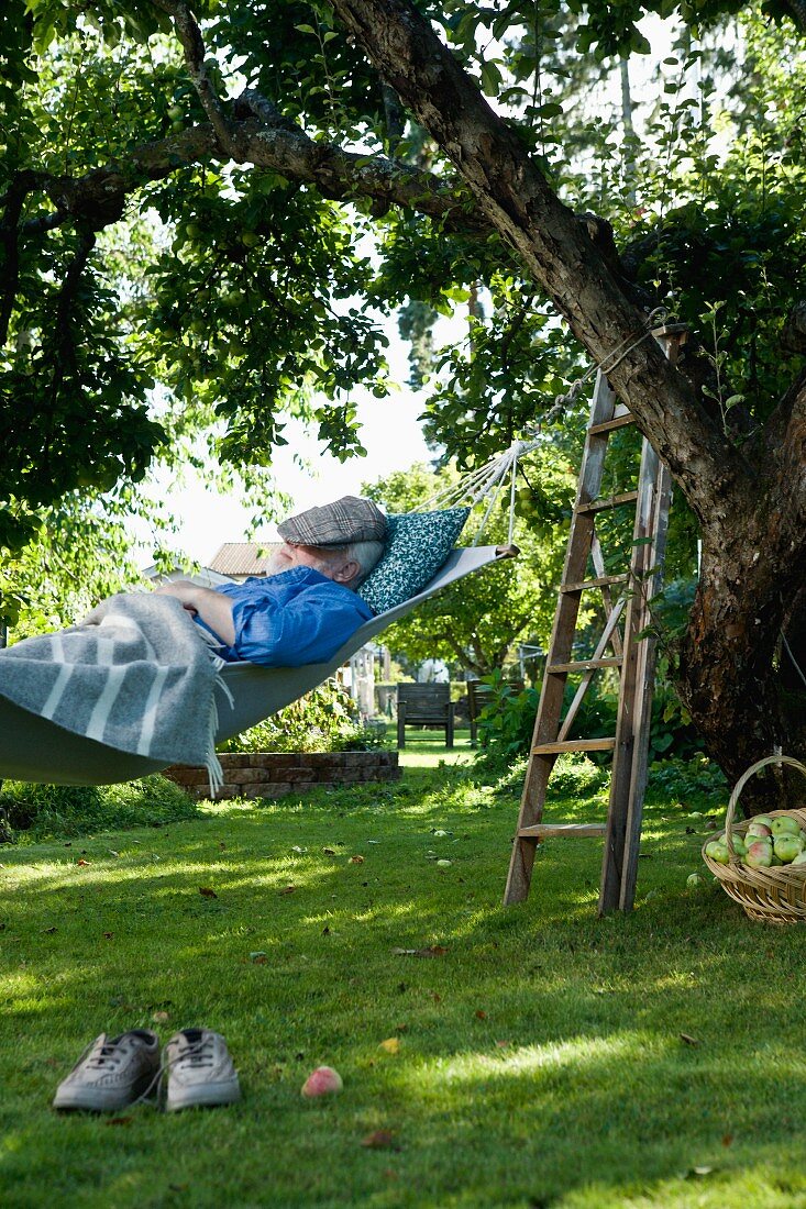 Old man lying in hammock in garden