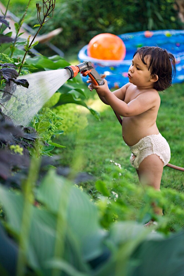 Little girl watering plants in garden