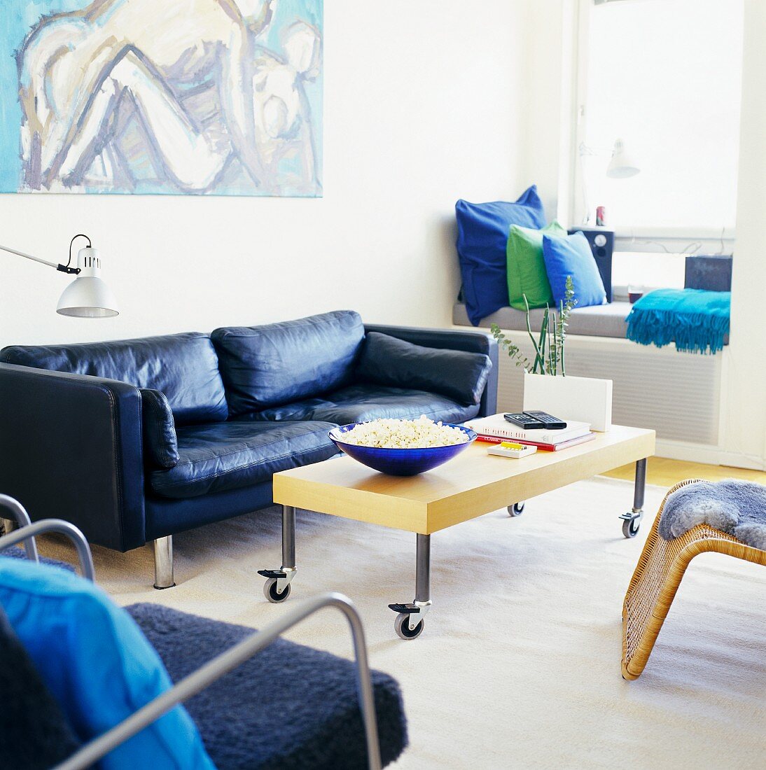 Wohnzimmer mit blauem Ledersofa und einer Schale Popcorn auf dem Tisch