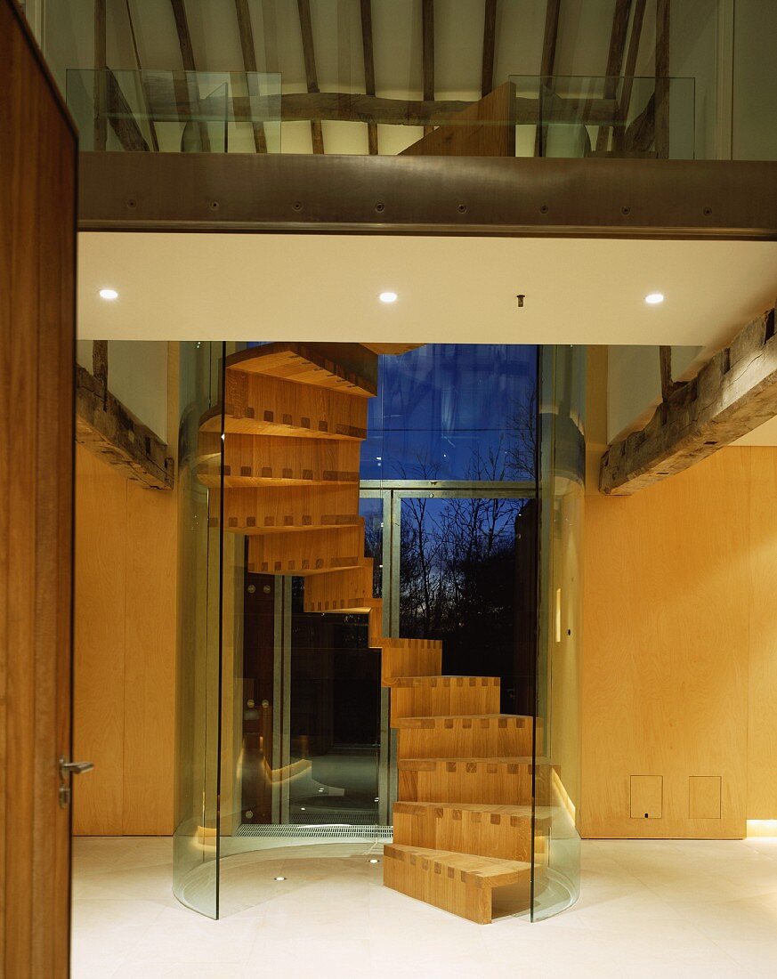 Wendeltreppe aus Holz mit gebogener Glaswand im umgebauten Bauernhaus