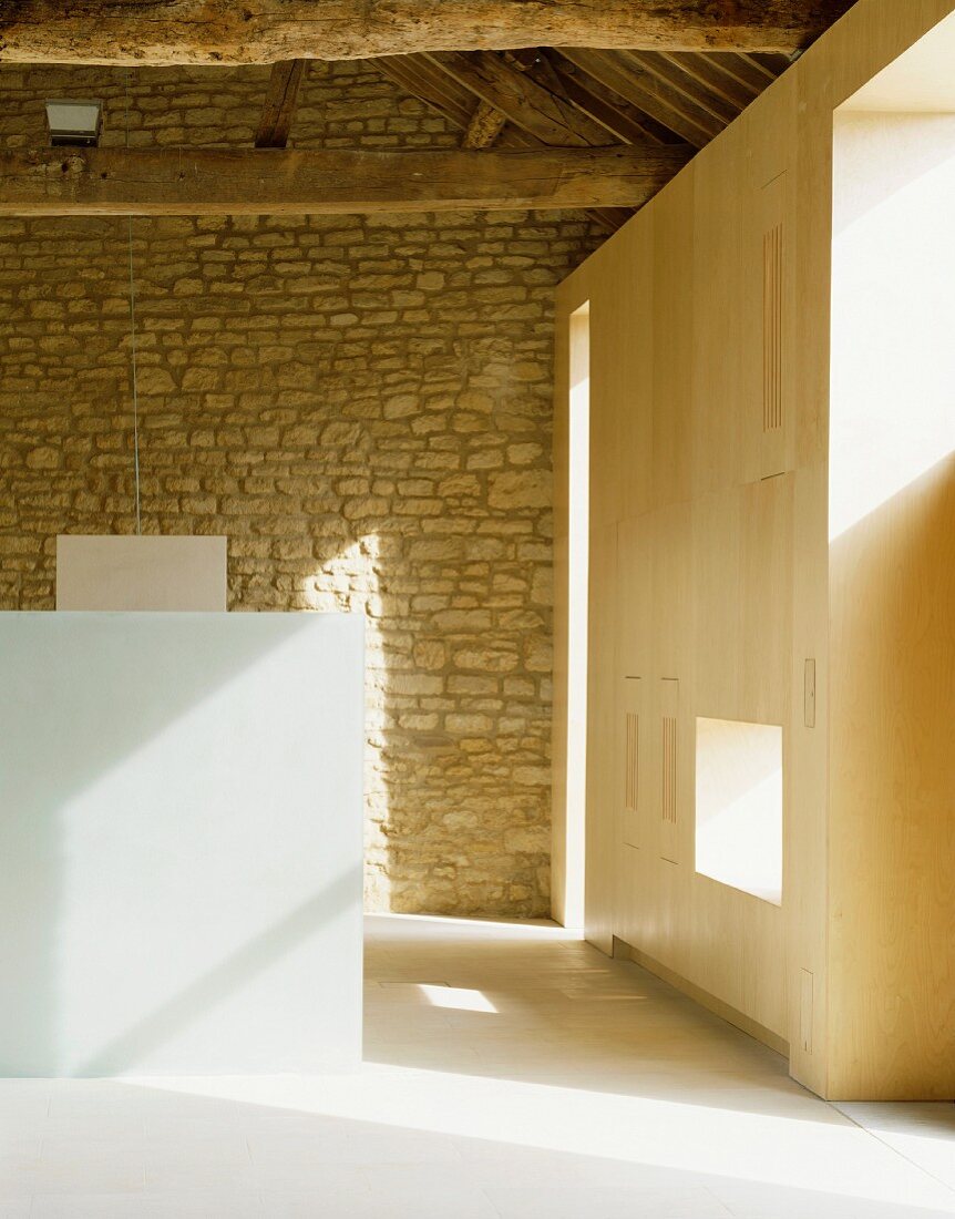 Im Designerstil ausgebauter Raum mit Einbauschrank aus Holz neben Natursteinwand