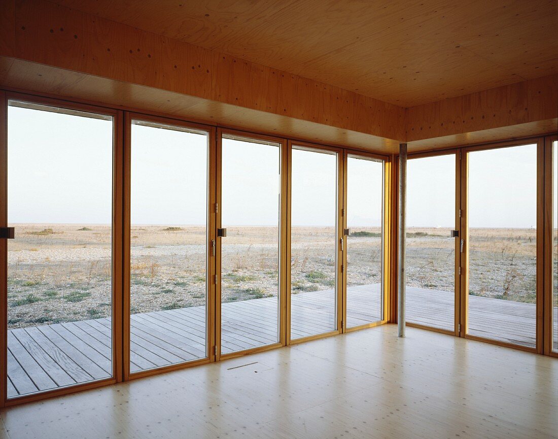Empty, wood-panelled room with terrace doors and view of landscape