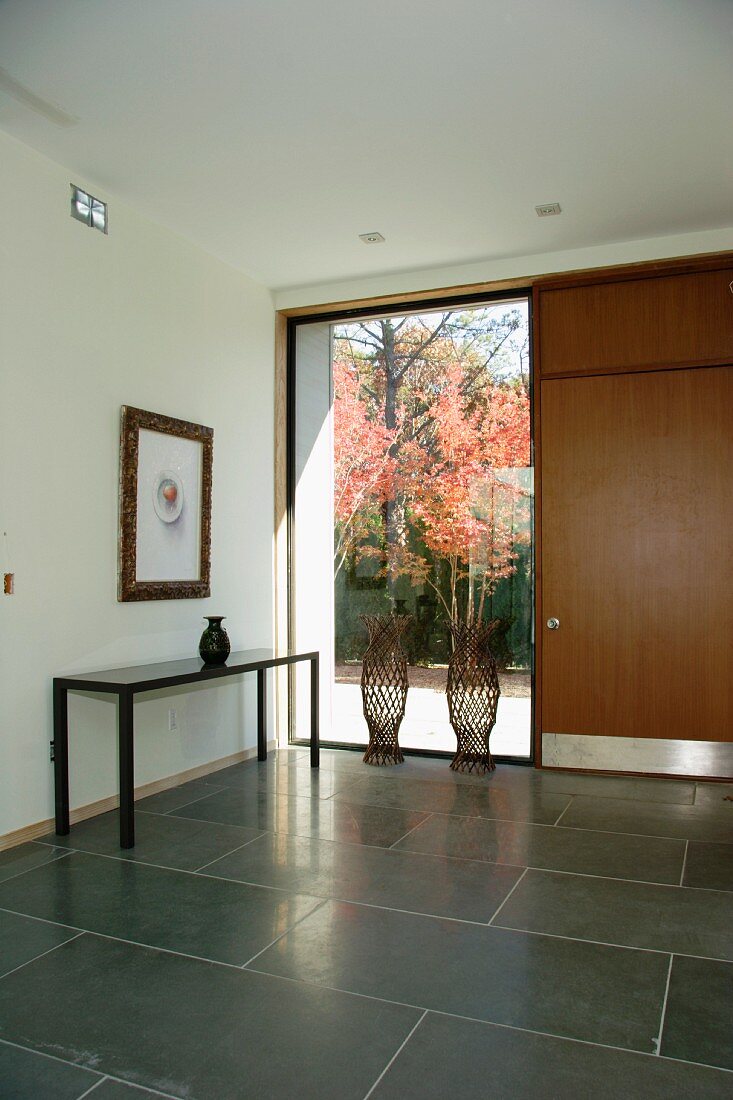 Modern foyer with large, grey tiles and floor-to-ceiling window next to front door